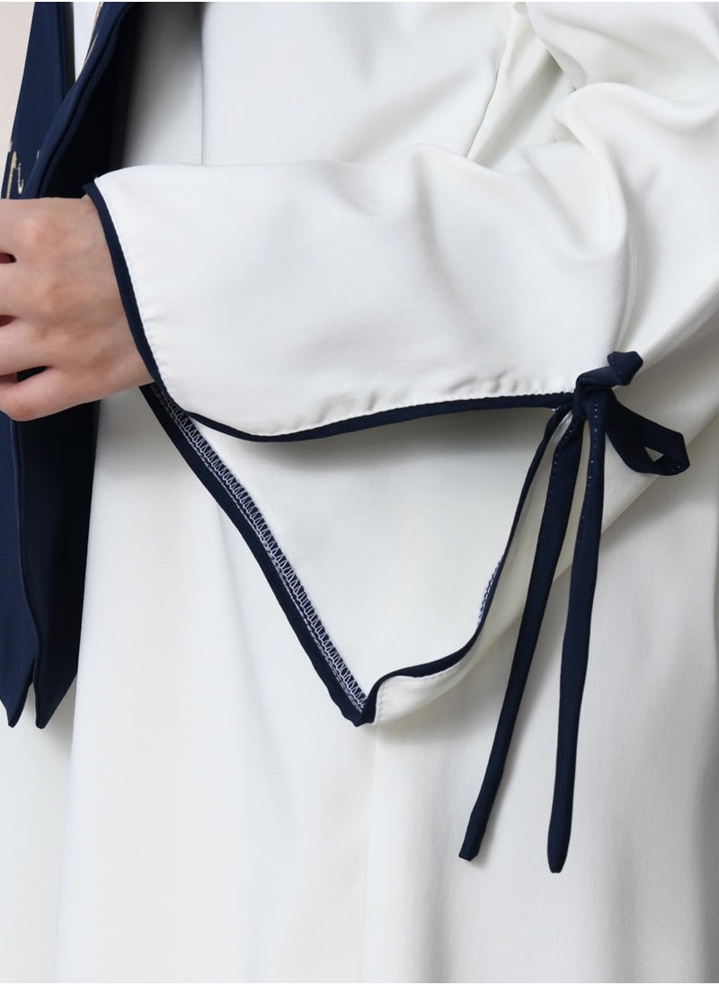 HAWRAA ABAYA - Graduation uniform: white abaya with wide open sleeves, decorated with a bow, with a plain scarf and cap, in dark navy blue - Image 1