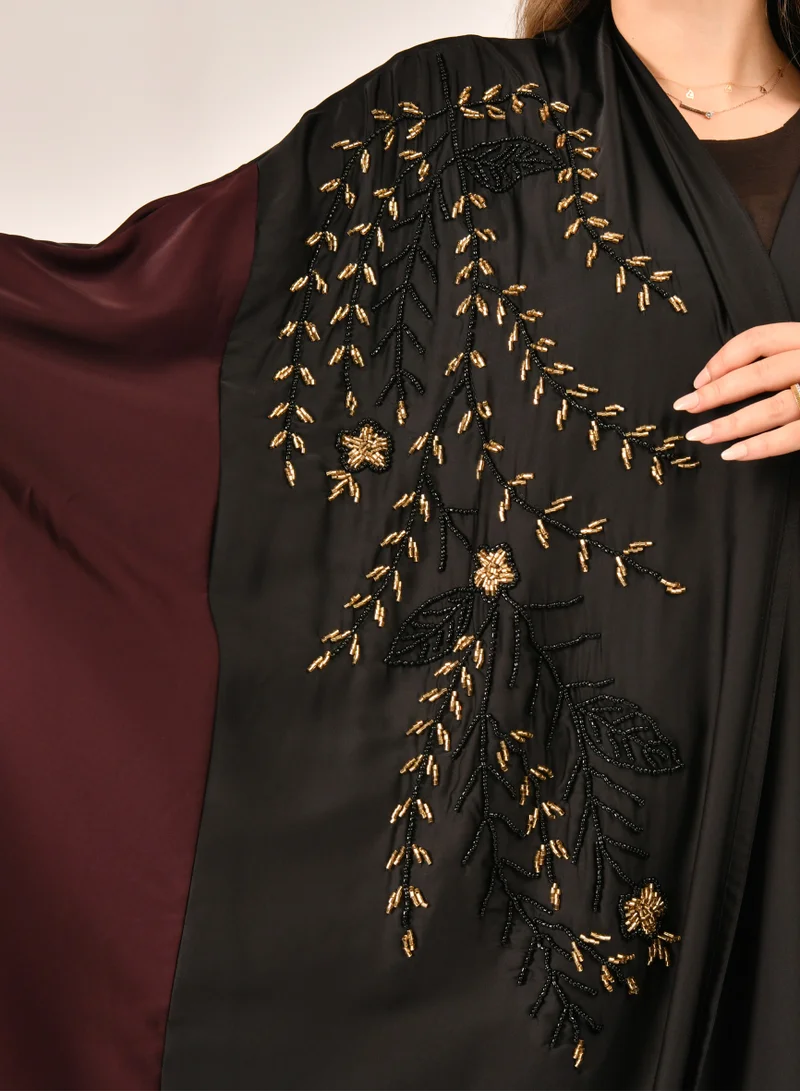HAWRAA ABAYA Bisht-style wrap abaya made of black and burgundy silk decorated with a luxurious sash on the side and includes a set veil