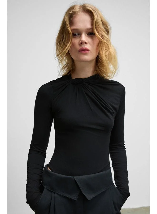 Grimelange HAZE Women's Round‑Neck Black Blouse with Front Knot Detail, Long Sleeves, Stretch Fabric, and Snap Closure.