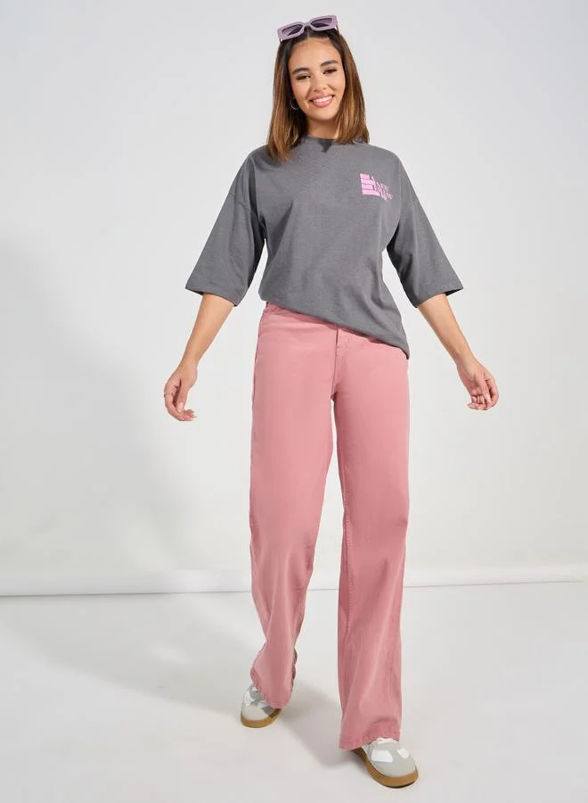 ستايلي تيشيرت واسع بتصميم ممزق وشعار وكتف ساقط