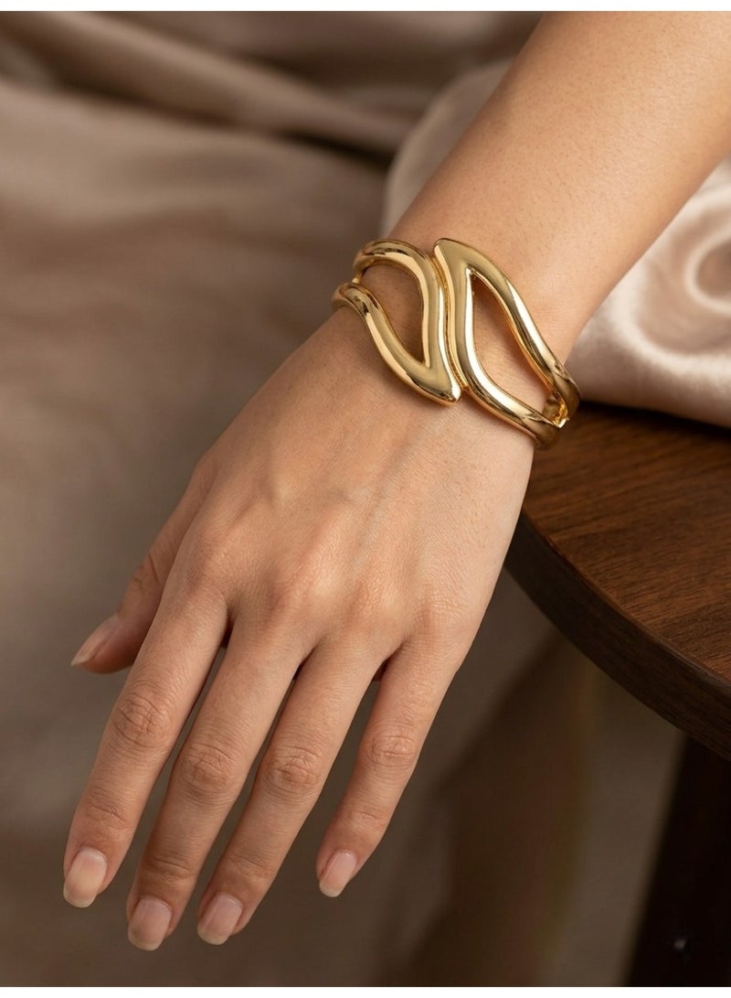 A stunning golden cuff featuring an artistic, sculptural design with interlocking organic curves for a bold and enchanting look