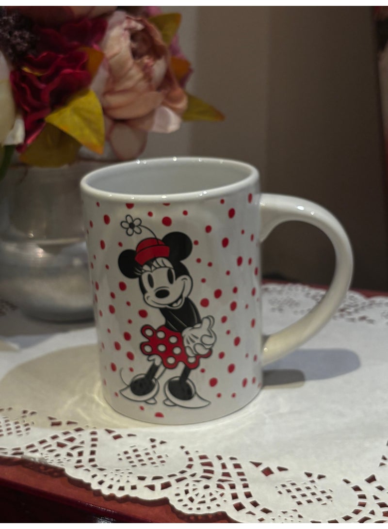 Minnie Mouse This is a charming ceramic mug in white, decorated with small red polka dots. The front side features the beloved cartoon character Minnie Mouse in a playful design, while the back side is adorned with a bright red heart, adding a touch of love and warmth to the mug. - Image 1