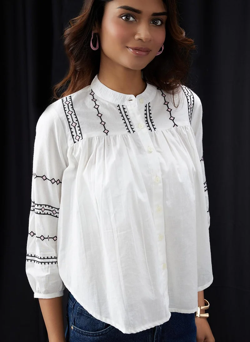 جلو باص بلوزة نسائية بيضاء بياقة ماندرين مطرزة وتفاصيل مزمومة ومكشكشة