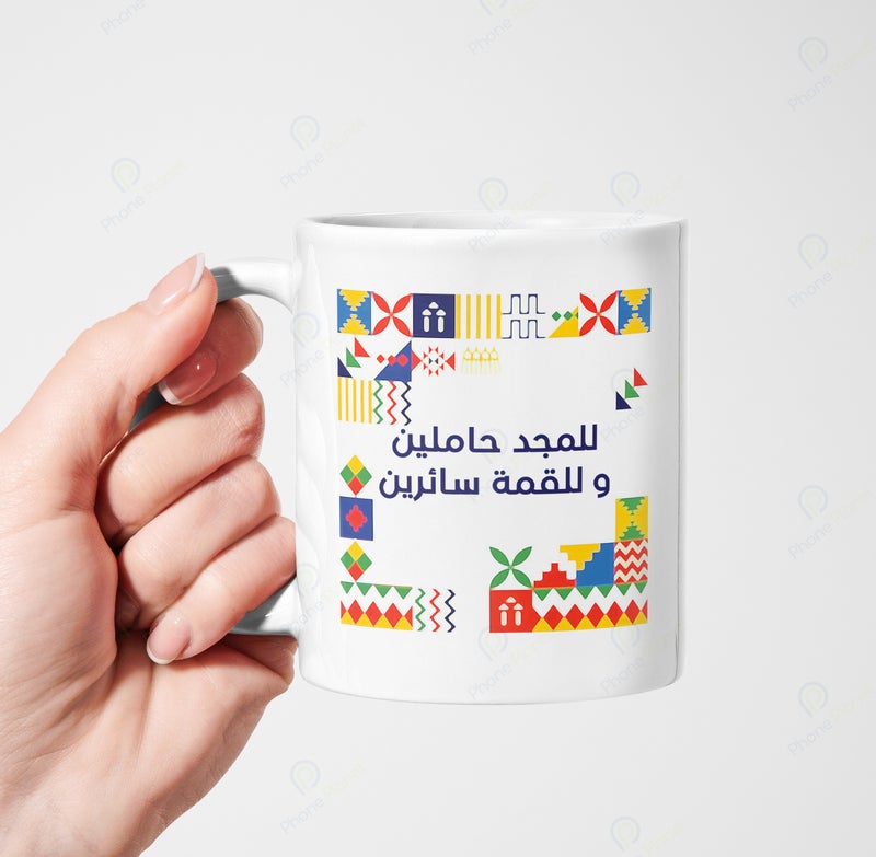 كوب من السيراميك مطبوع عليه عبارة للمجد حاملين وللقمة سائرين ويتميز بمقبض مريح