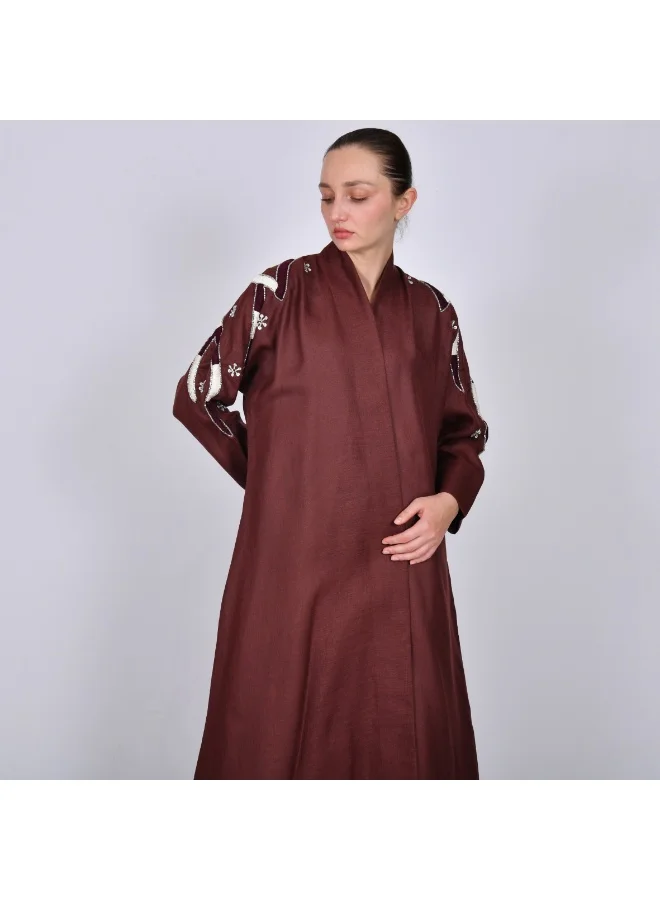 HAWRAA ABAYA A maroon half-cloche abaya decorated with embroidery and prominent beading on the sleeves.