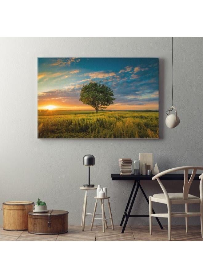 هوم جاليري زاوية واسعة لقطة شجرة واحدة تنمو السماء الملبدة بالغيوم أثناء غروب الشمس محاطة بالعشب تابلوه كانفاس مطبوع - Image 2