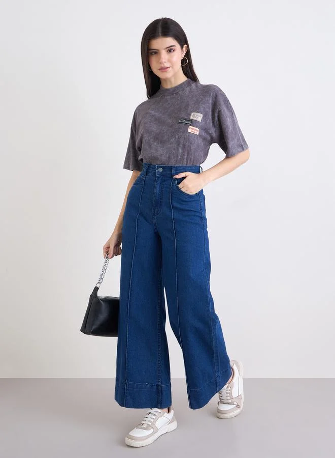 ستايلي تيشيرت واسع بتفاصيل مشطوفة ومزين بشارة