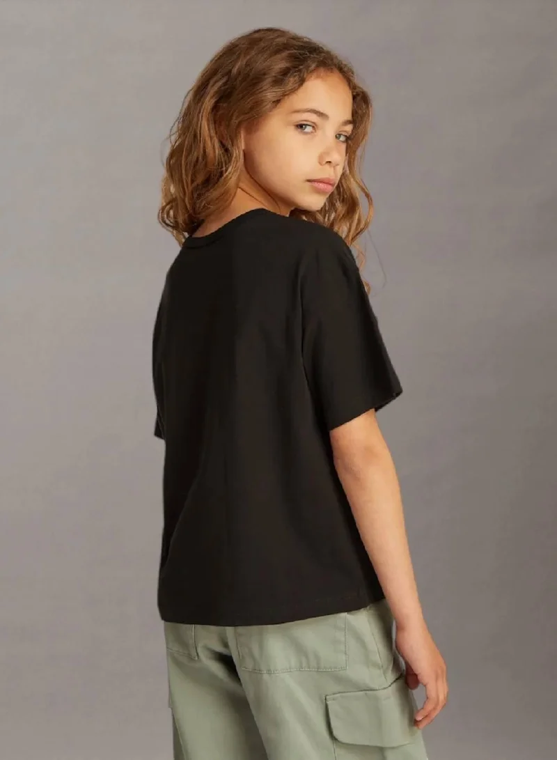 كالفن كلاين جينز تيشرت واسع مزين بشعار كلفن كلاين