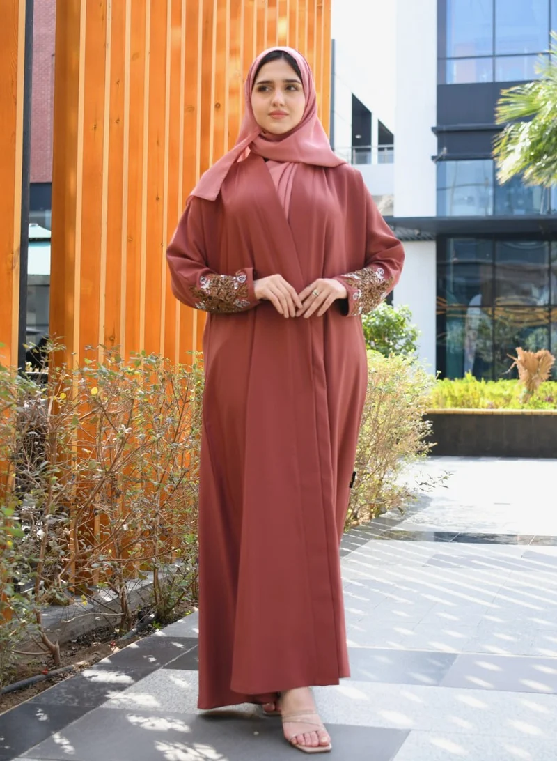 HAWRAA ABAYA A quarter-cloche wrap abaya in a calm orange color with hand embroidery on the sleeves.