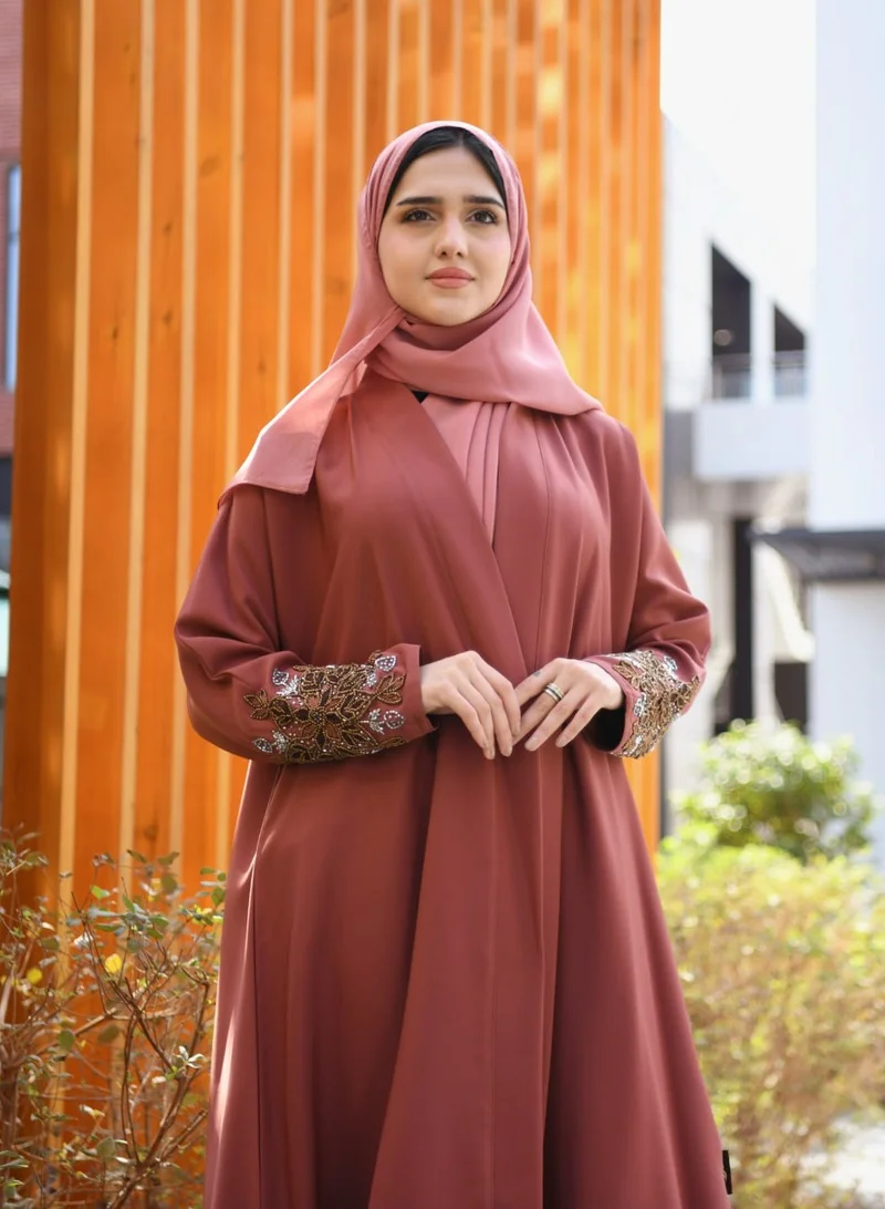 HAWRAA ABAYA A quarter-cloche wrap abaya in a calm orange color with hand embroidery on the sleeves.