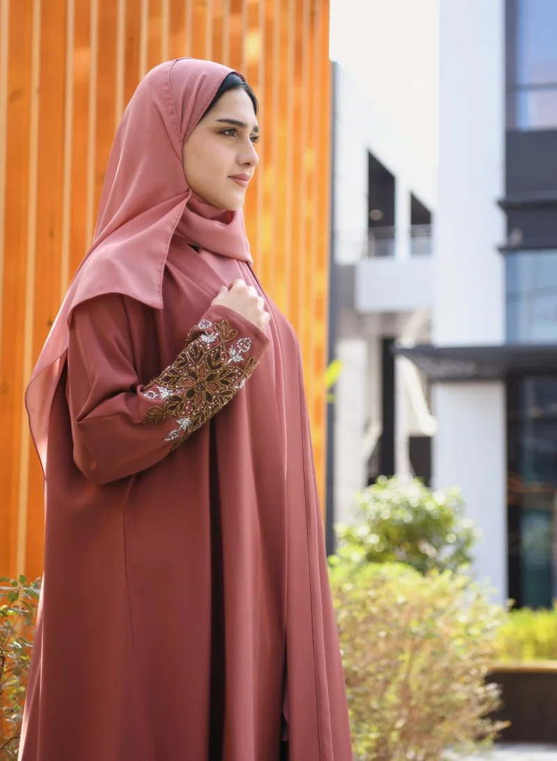 HAWRAA ABAYA A quarter-cloche wrap abaya in a calm orange color with hand embroidery on the sleeves.