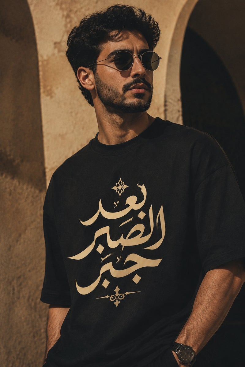 تي شيرت رجالي أسود بقصة واسعة وطبعة خط عربي أنيقة تصميم كاجوال عصري بأكمام قصيرة وياقة دائرية - Image 1