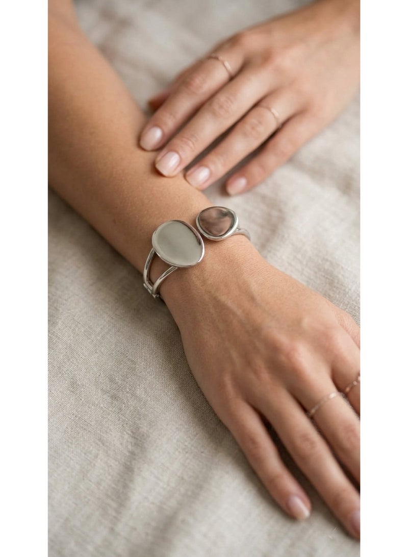 A sophisticated open silver cuff bracelet featuring a modern design with two asymmetrical circular ends and a smooth polished finish for a distinctive look