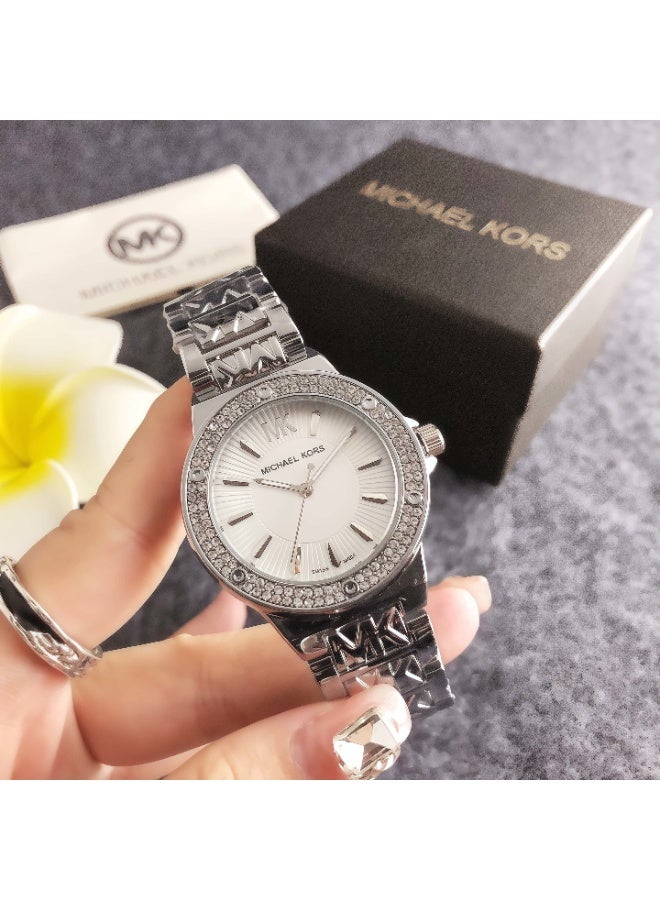 MK ساعة ميخايل كورس النسائية باللون الفضي مع إطار مزين بالكريستال وشعار - سوار مفصل