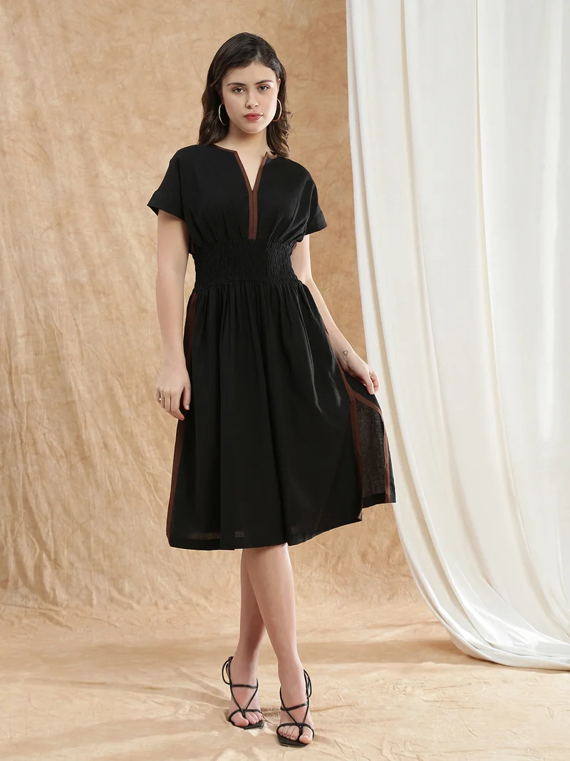 جلو باص فستان نسائي أسود بياقة على شكل حرف  وأكمام ممتدة، سادة، بخصر مطاطي وجانب مشقوق، بقصة واسعة من الأسفل وطول متوسط