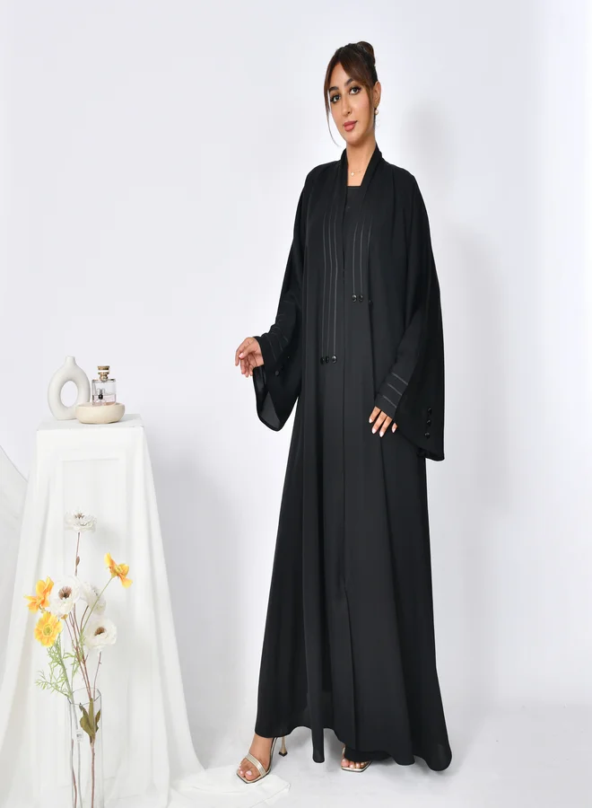 HAWRAA ABAYA Cloche abaya with closed buttons, decorated with ribbons and buttons