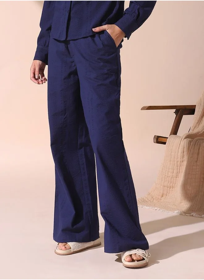 Dennis Lingo Women blue loose fit solid cotton blend trousers with button closure- where comfort meets classic charm.