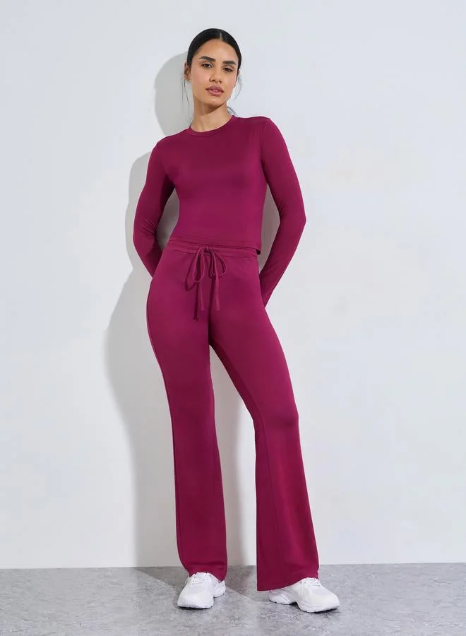 Styli Active Burgundy Solid Long Sleeves Crop Top And Flared Leggings Active Set