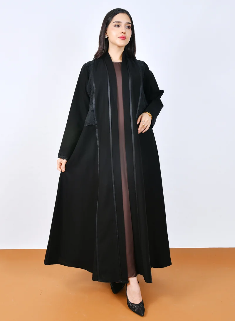 عبايات حوراء عباية بنص كلوش أنيقة بتصميم متداخل مع قماش ركامة مخرم يزينها شريط ساتان ناعم على طول الواجهة الأمامية