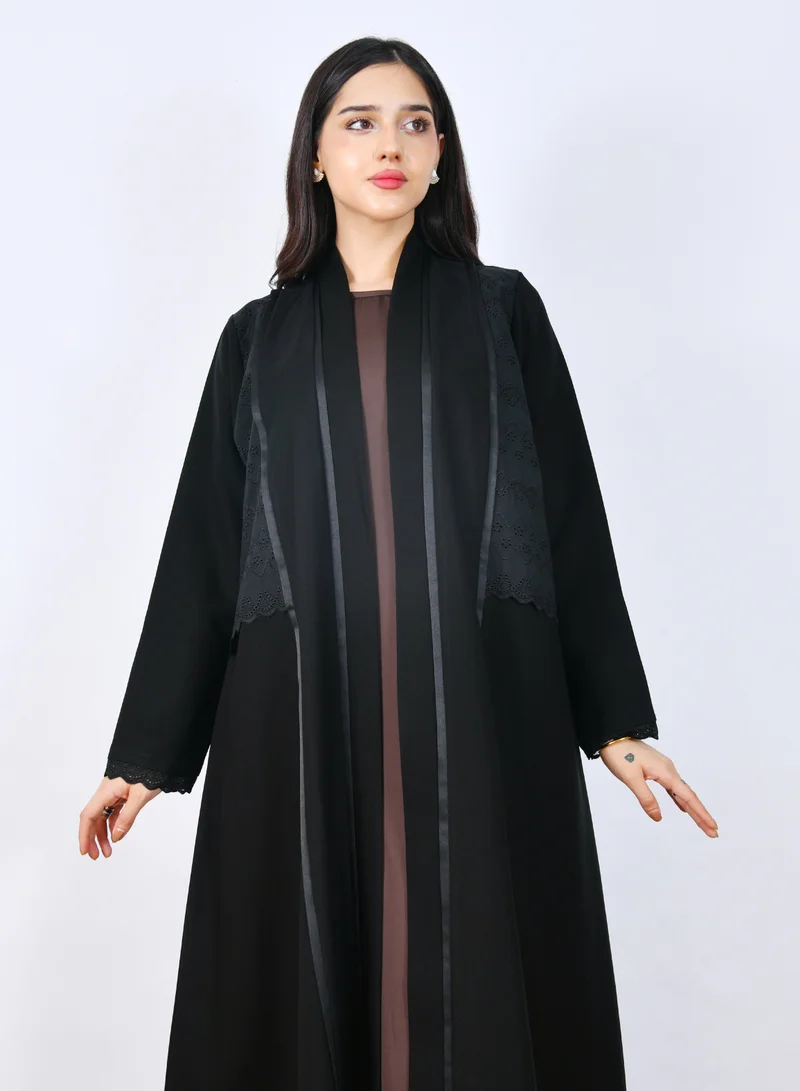عبايات حوراء عباية بنص كلوش أنيقة بتصميم متداخل مع قماش ركامة مخرم يزينها شريط ساتان ناعم على طول الواجهة الأمامية