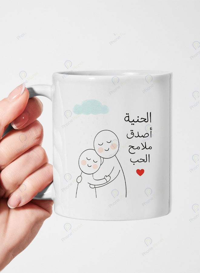 كوب من السيراميك مطبوع عليه عبارة الحنية أصدق ملامح الحب ويتميز بمقبض مريح