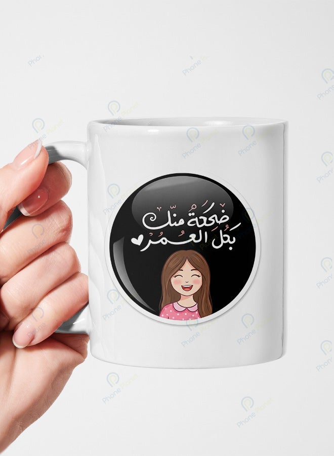 كوب من السيراميك مطبوع عليه عبارة ضحكة منك بكل العمر ويتميز بمقبض مريح