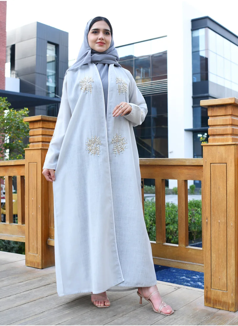 HAWRAA ABAYA Light blue wrap abaya decorated with a prominent brocade and qitan on the edges of the abaya and the sleeves