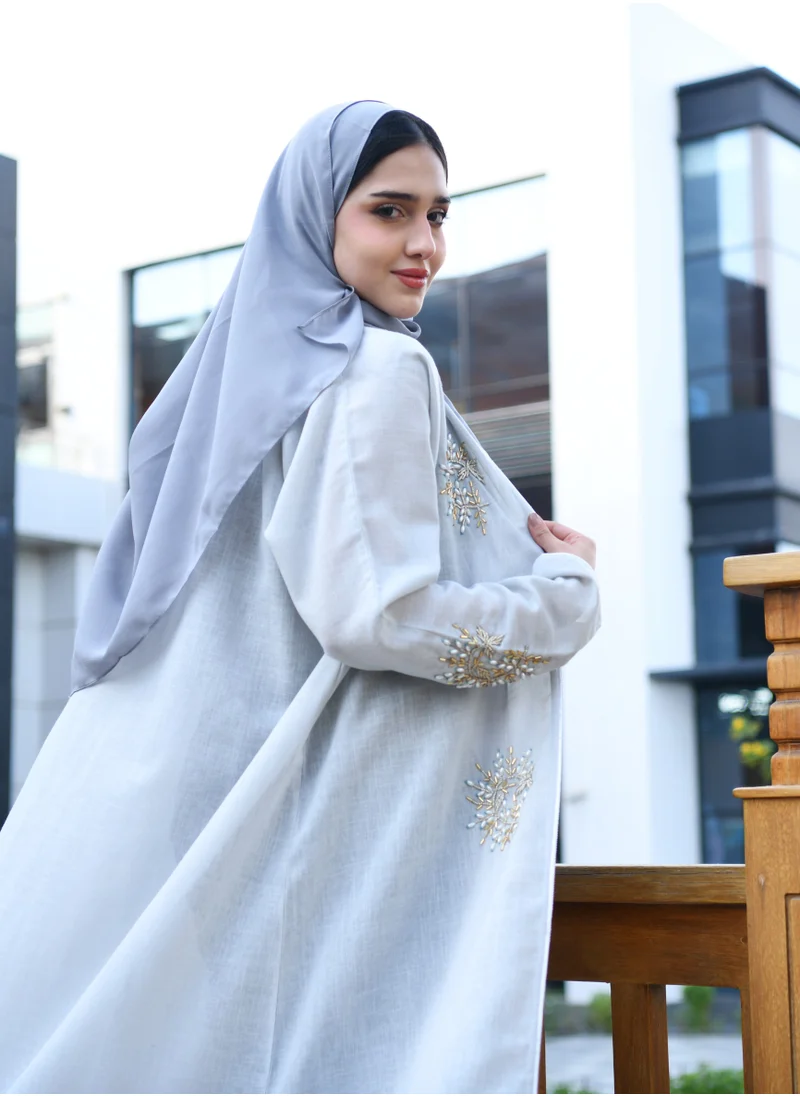 HAWRAA ABAYA Light blue wrap abaya decorated with a prominent brocade and qitan on the edges of the abaya and the sleeves