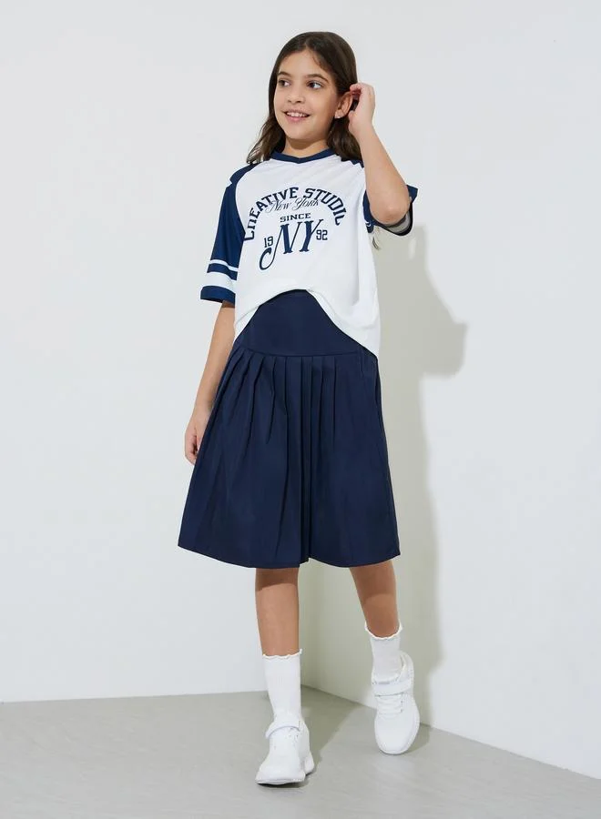 Styli Teen Girls Graphic Print Oversized T-Shirt and Pleated knee Length Skirt Set
