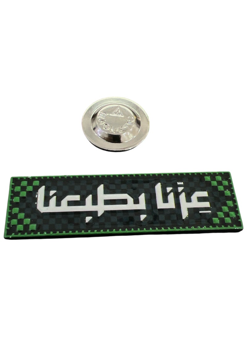 سعودي بروش أخضر مكتوب عليه 'عزنا بطبعنا', إكسسوار مميز لليوم الوطني السعودي والمناسبات الوطنية