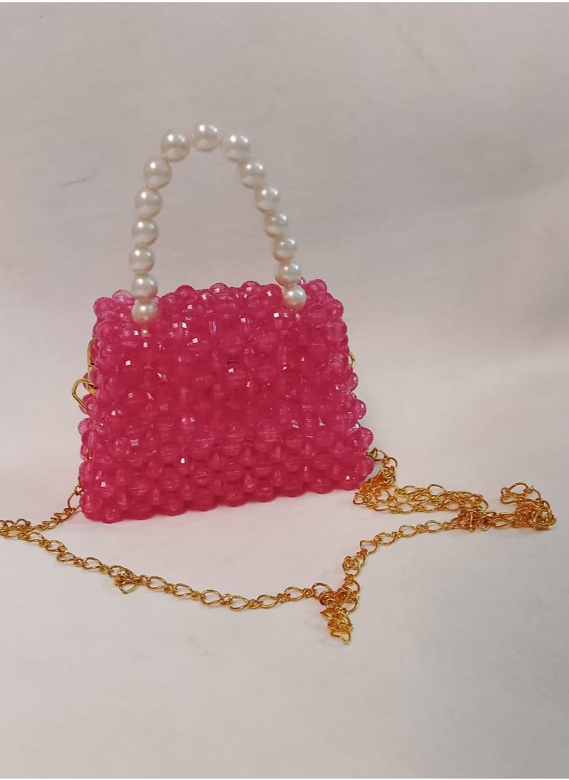 A hand-made bag made o crystal fuchsia in color with an imported pearl handle and a long one meter long gold-plated metal strap. The bag is 13 cm wide and 9 cm long. It is very suitable for children for daily use and evening parties