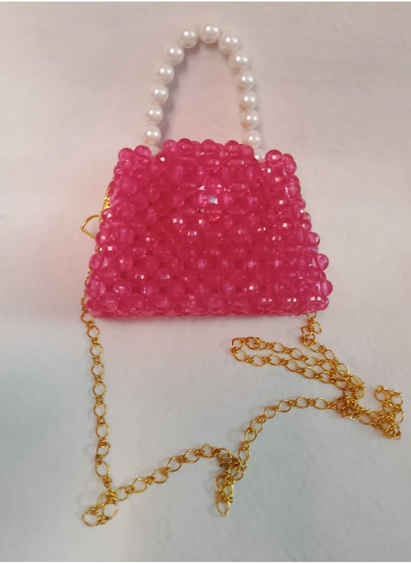 A hand-made bag made o crystal fuchsia in color with an imported pearl handle and a long one meter long gold-plated metal strap. The bag is 13 cm wide and 9 cm long. It is very suitable for children for daily use and evening parties