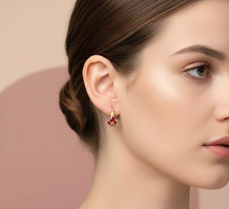 Gold earrings adorned with square ruby-red stones, featuring a striking geometric design reminiscent of a precious "gift." A piece that combines delicacy with bold color for a captivating look. - Image 2
