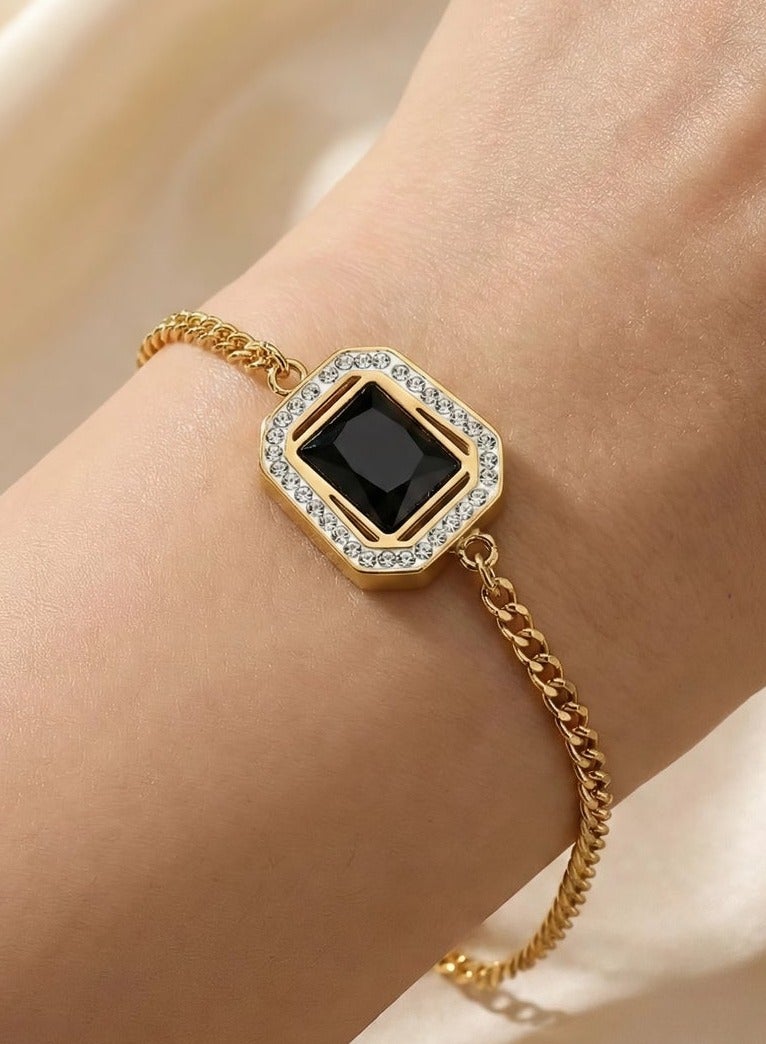 A gold-tone bracelet crafted from rust-resistant stainless steel, featuring a regal black stone surrounded by a sparkling zircon-encrusted bezel. A delicate and luxurious design, with an adjustable clasp for a perfect fit. - Image 1