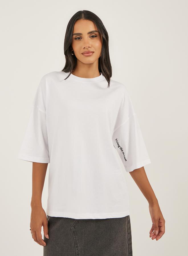 ستايلي تيشيرت واسع بطباعة شعار وأكتاف ساقطة - Image 1