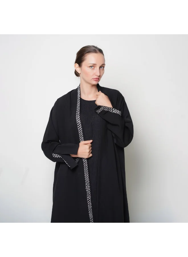 HAWRAA ABAYA Black wrap abaya with a flowing cut and white embroidery.