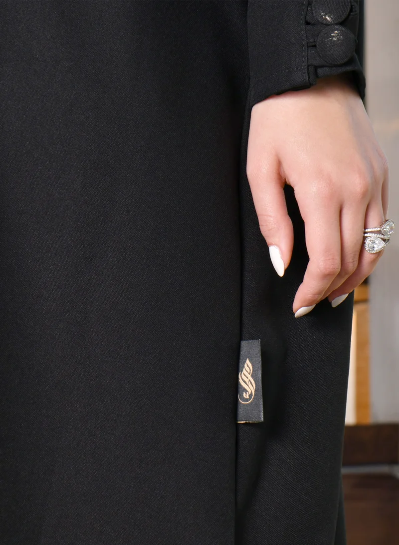 HAWRAA ABAYA Black abaya with a zipper closure and a high collar with narrow sleeves decorated with buttons