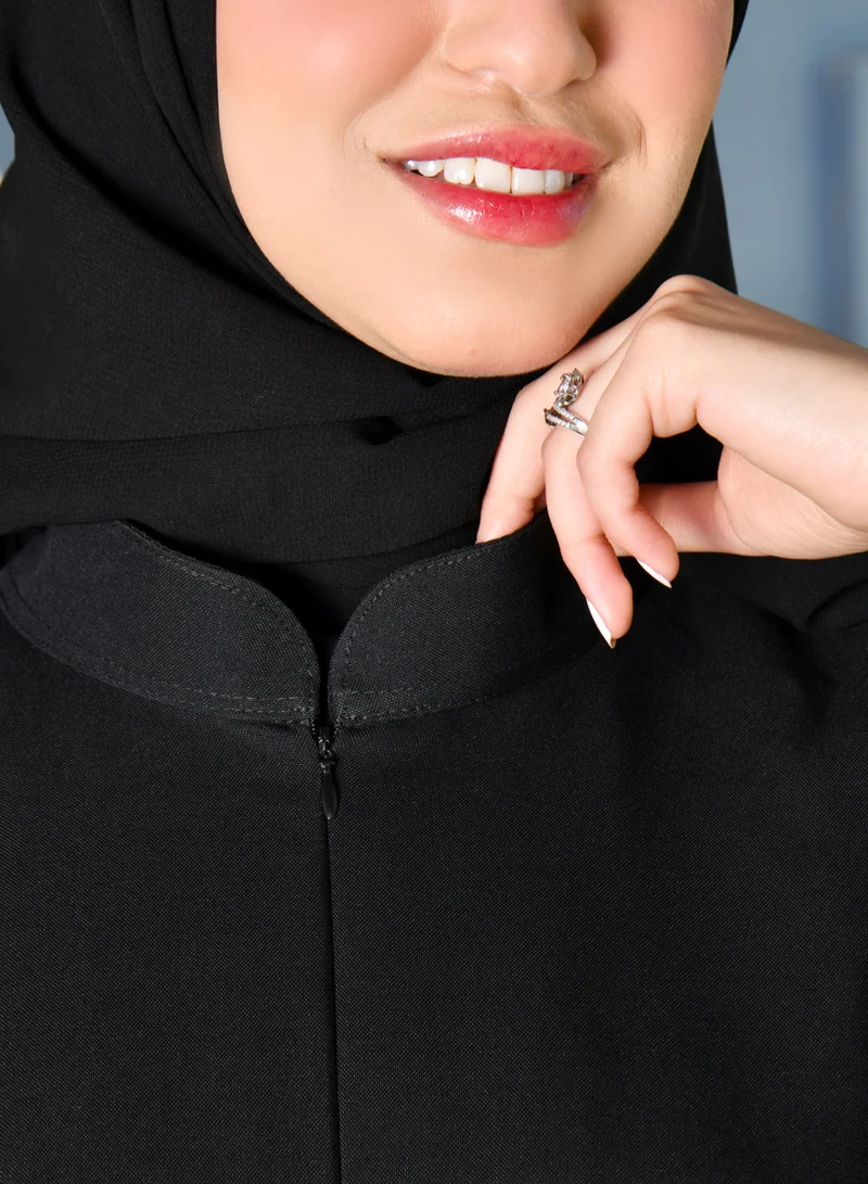 HAWRAA ABAYA Black abaya with a zipper closure and a high collar with narrow sleeves decorated with buttons