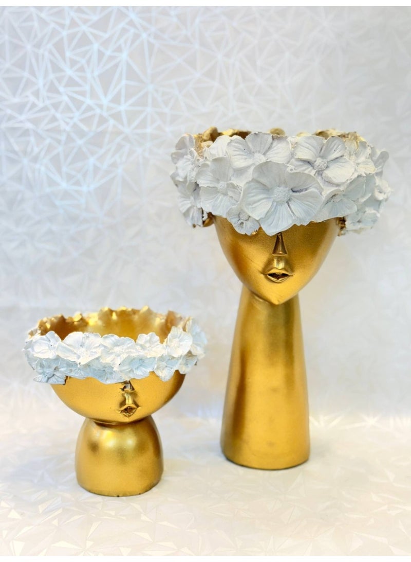 ناما لأصيصان مصنوعان من مادة الراتنج بلمسة نهائية لامعة باللون الذهبي، وتتوجان بتفاصيل بارزة ومذهبة على شكل باقة من الزهور، مع لمسة بيضاء مميزة تبرز جمال التصميم.