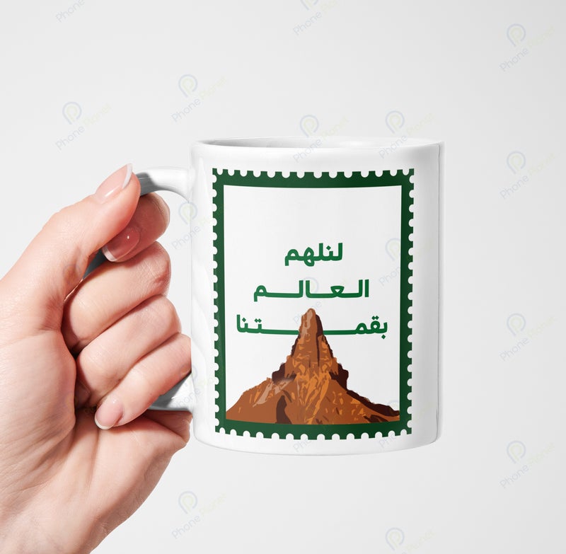 كوب من السيراميك مطبوع عليه عبارة لنلهم العالم بقمتنا ويتميز بمقبض مريح