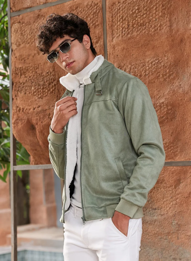 كامبوس سوترا جاكيت بومبر رجالي من جلد الغزال مبطن بالصوف بلون الزيتون مع ياقة مدببة وأكمام مضلعة وإغلاق بسحاب وحافة مستقيمة مضلعة.