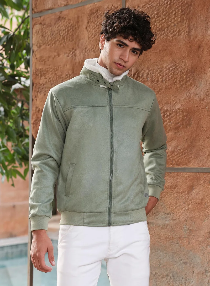 كامبوس سوترا جاكيت بومبر رجالي من جلد الغزال مبطن بالصوف بلون الزيتون مع ياقة مدببة وأكمام مضلعة وإغلاق بسحاب وحافة مستقيمة مضلعة.