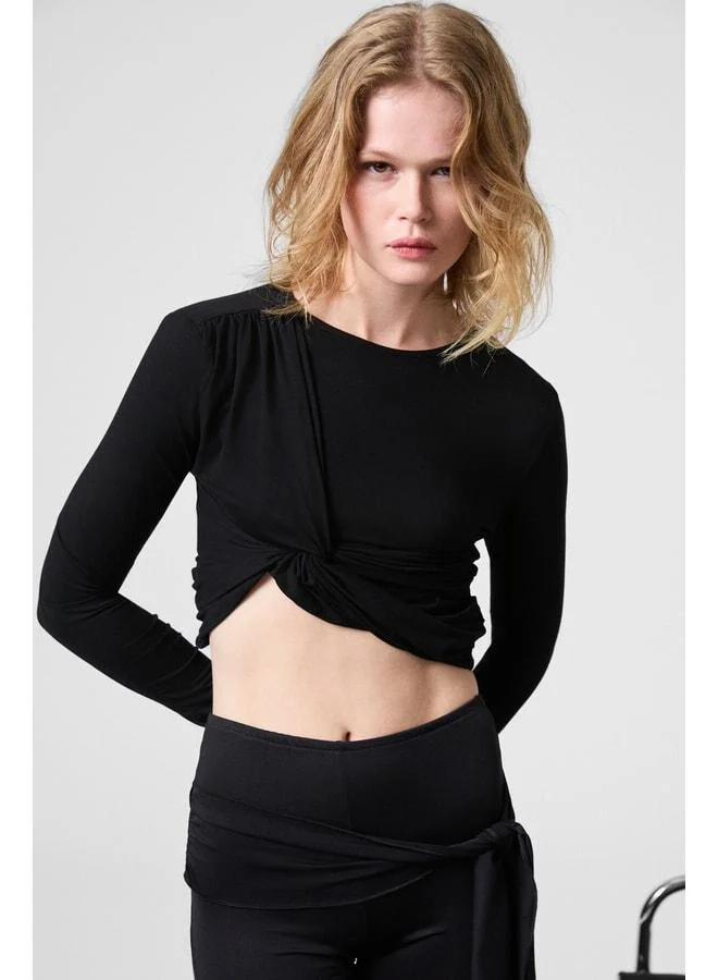 GRIMELANGE SLATE Women's round‑neck crop black blouse with front knot detail and body‑hugging stretch fabric.