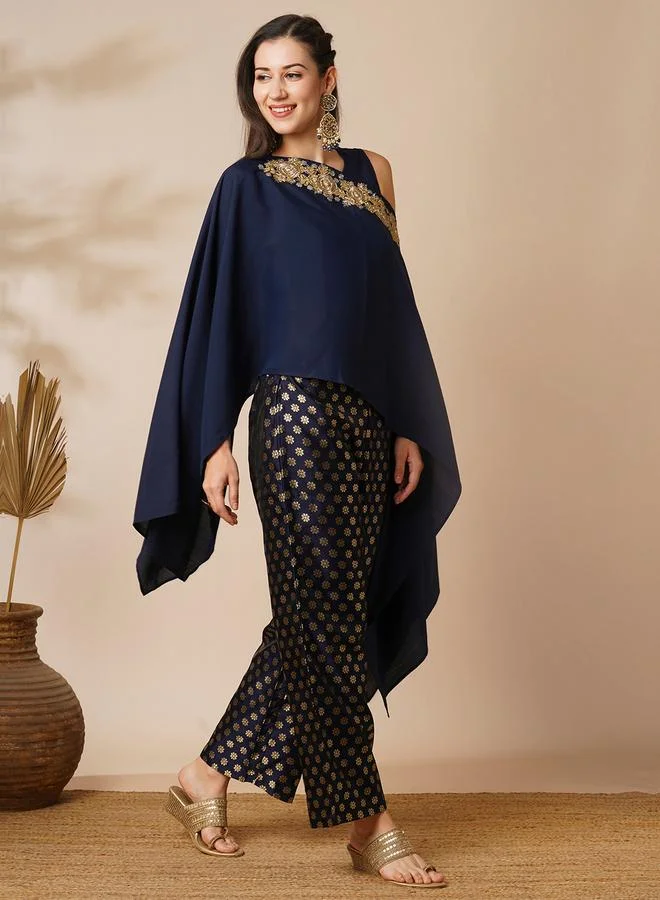 جلو باص طقم منسق من بلوزة بونشو بتفاصيل دانتيل وبنطال بطبعة رقائق معدنية