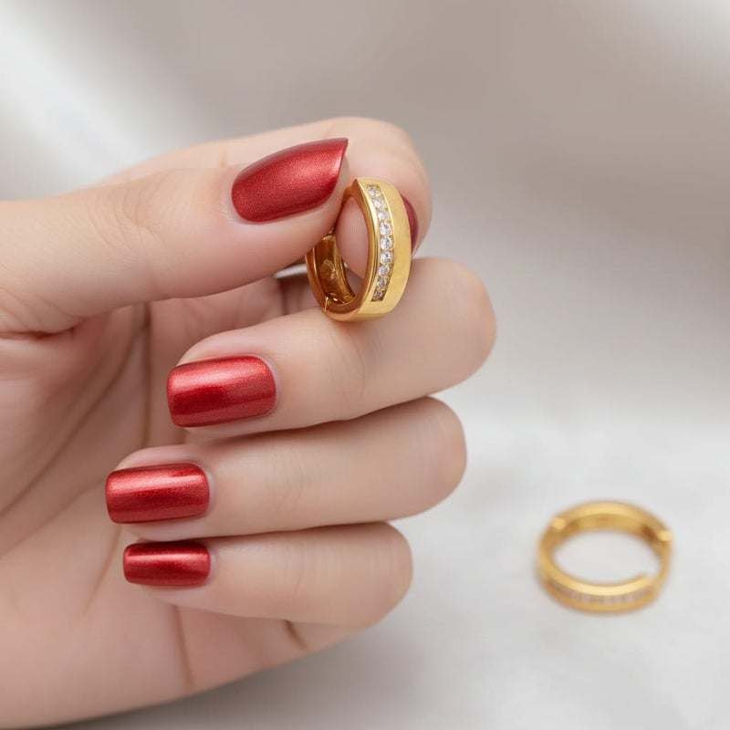 حلق رقيق مطلي باللون الذهبي ، بتصميم زهرة أنيقة. مرصع بـ حجر أحمر مركزي، تحيط به فصوص لامعة. يتميز بـ دلاية متدلية على شكل كرة ذهبية ناعمة. - Image 3