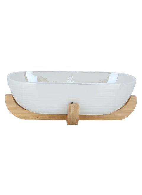 Deep oval beige porcelain serving bowl with a wooden base