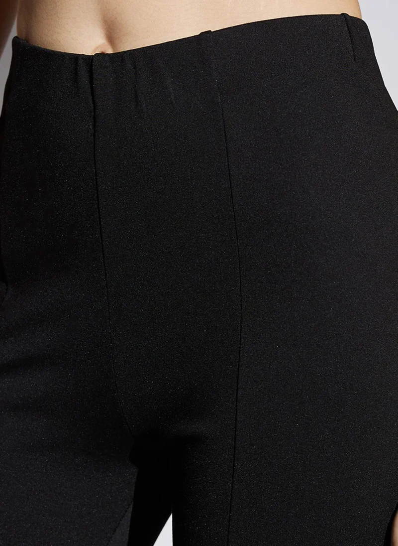 جلو باص بنطلون نسائي أسود لامع بخصر متوسط قابل للتمدد وفتحة أمامية واسعة مناسب للحفلات