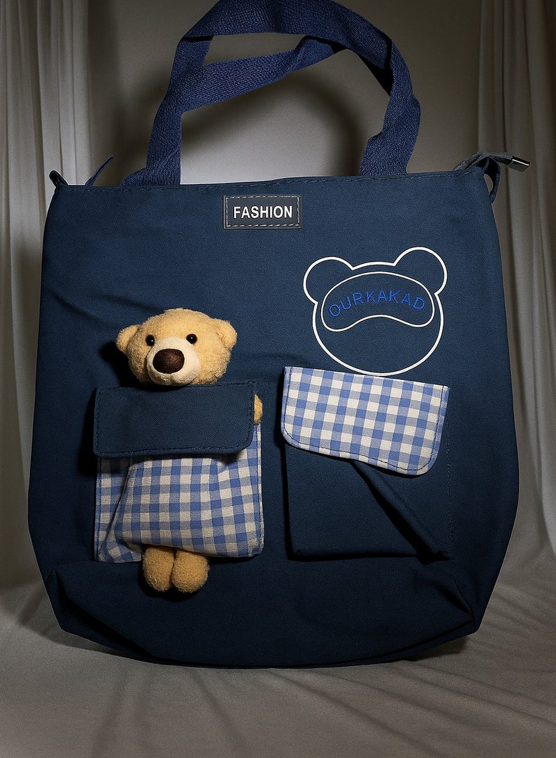 فاشون شنطة كتف حمل لطيفة من القماش و النايلون متعددة الاستخدامات مع سحاب لحفظ الاشياء داخل الحقيبة و جيبين خارجيين فيه نقش كاروهات و  دبدوب لطيف سعة كبيره يستخدمها الفتيات المراهقات او الامهات او الاطفال سهلة التنظيف تحفظ غيرات الاطفال او المقنيات الشخصية او العاب البحر او المكياج او العطور في السفر او الخروج اليومي ايضا مثاليه للهدايا لون ازرق كحلي - Image 1