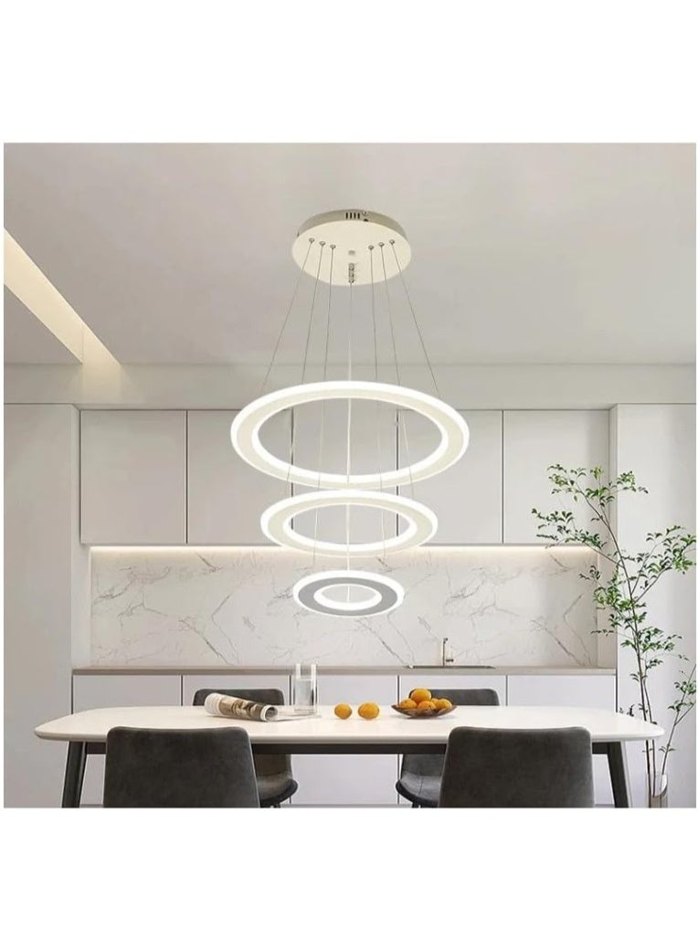 Modern Minimalist Kitchen Dining Area with Sleek White Circular LED Pendant Lights, Elegant Marble Backsplash, Clean White Cabinetry, Cozy Dark Gray Chairs, and a Touch of Greenery for a Stylish Look