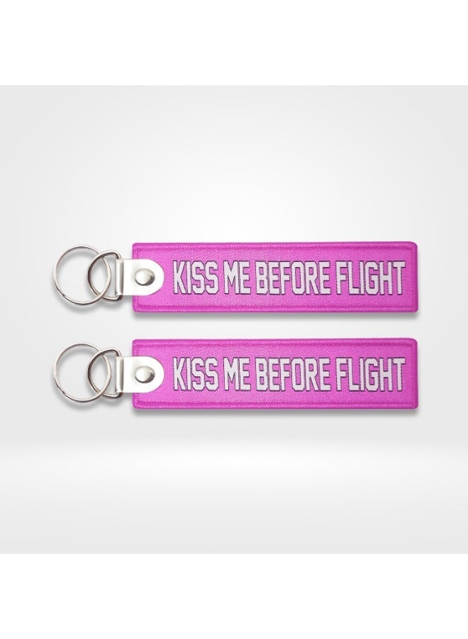 ميدالية مفاتيح قماشية بعبارة "KISS ME BEFORE FLIGHT" (نص باللونين الوردي والأبيض)